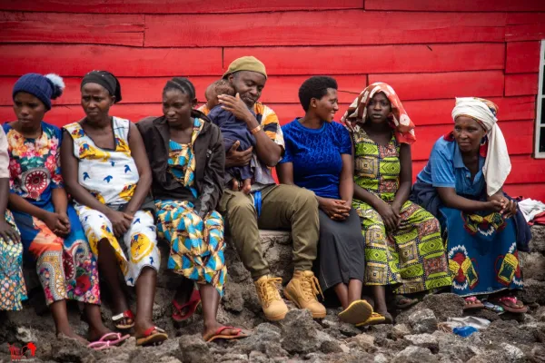 Image of 7 people sitting in front of a red background